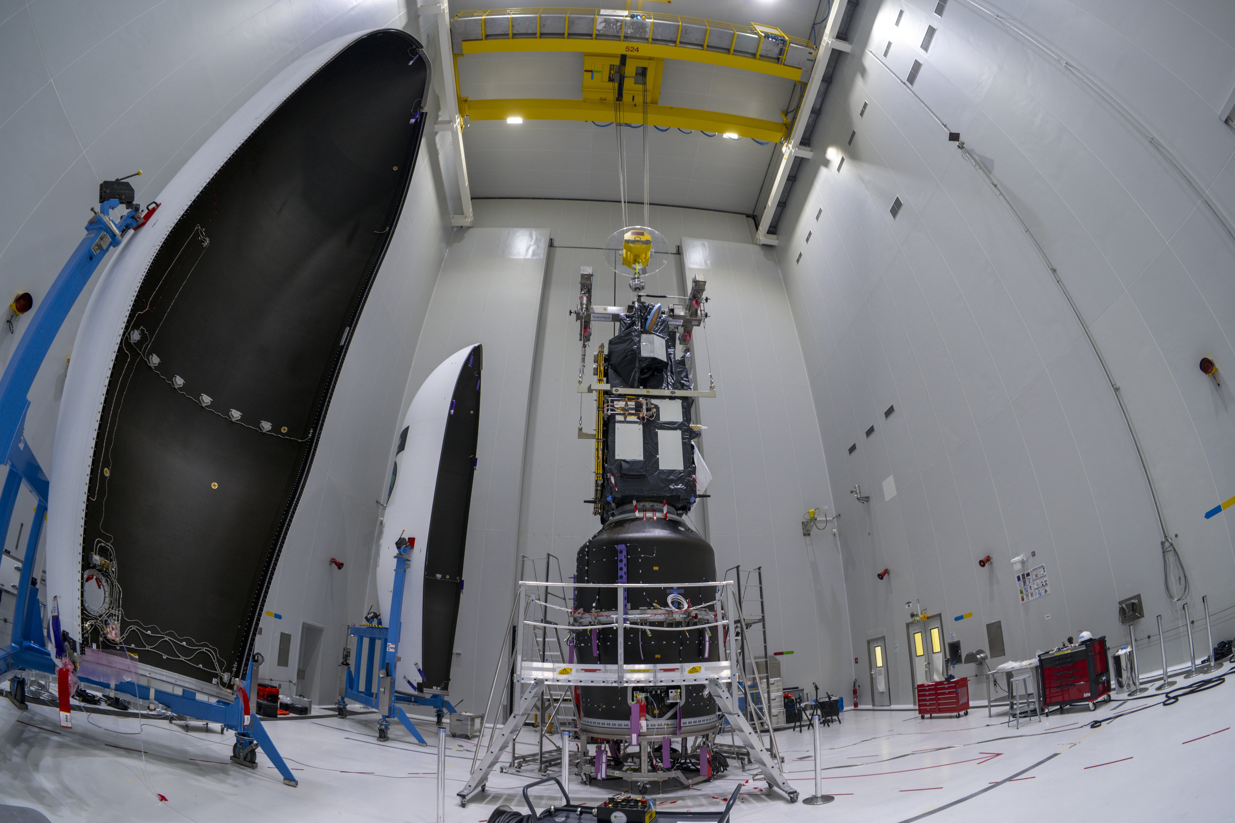ESA-persfoto van Sentinel-3C en FLEX in de assemblagehal, met de geopende raketkap ernaast.